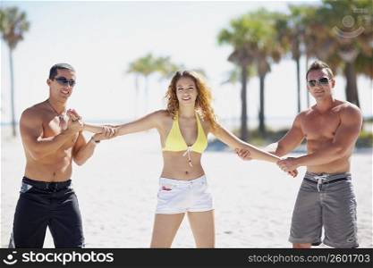 Portrait of a young woman with a mid adult man and a young man standing on the beach