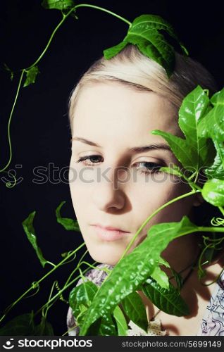 Portrait of a young woman with a passion fruit plant on a black background