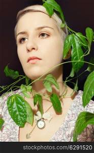 Portrait of a young woman with a passion fruit plant on a black background