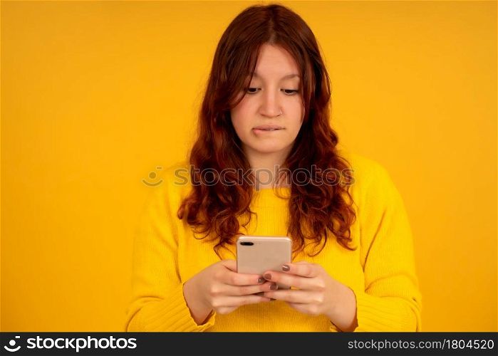 Portrait of a young woman with a worried expression on her face while using a mobile phone.