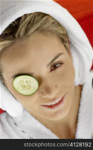 Portrait of a young woman with cucumber slices on her eyes
