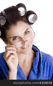 Portrait of a young woman with curlers in her hair adjusting her eyeglasses