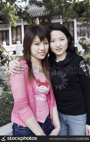 Portrait of a young woman with her arm around her friend