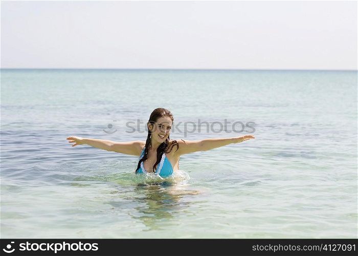 Portrait of a young woman with her arm outstretched in the sea