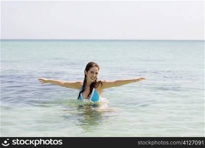 Portrait of a young woman with her arm outstretched in the sea