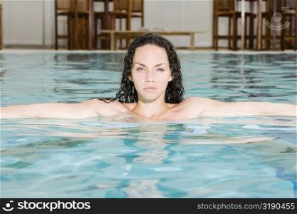 Portrait of a young woman with her arms outstretched in a swimming pool