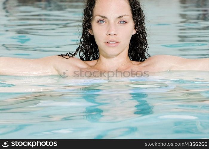 Portrait of a young woman with her arms outstretched in a swimming pool