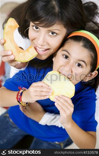 Portrait of a young woman with her daughter eating fruits