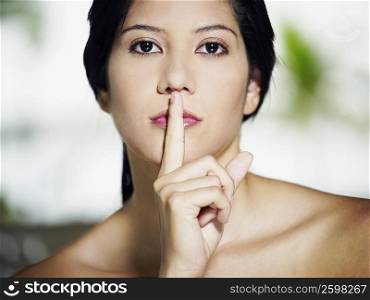 Portrait of a young woman with her finger on her lips