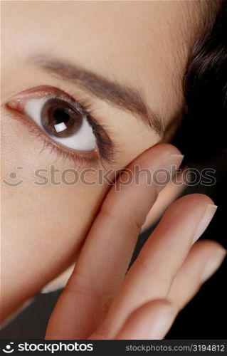 Portrait of a young woman with her fingers near her eye
