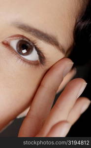 Portrait of a young woman with her fingers near her eye