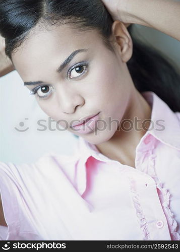 Portrait of a young woman with her hands behind her head