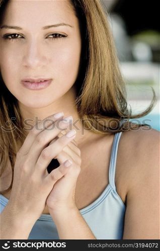 Portrait of a young woman with her hands clasped