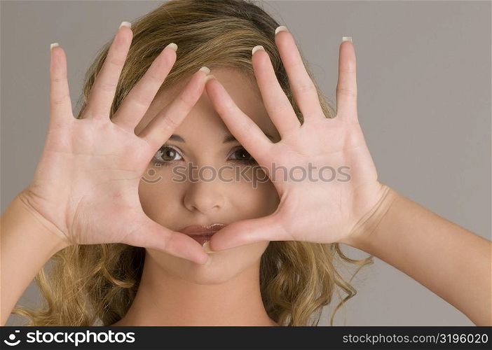 Portrait of a young woman with her hands over her face