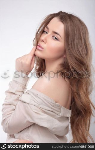 Portrait of a young woman with long hair and a shirt. Naked shoulder.