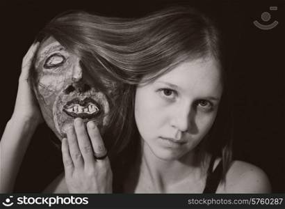 Portrait of a young woman with spooky theatrical mask in hand