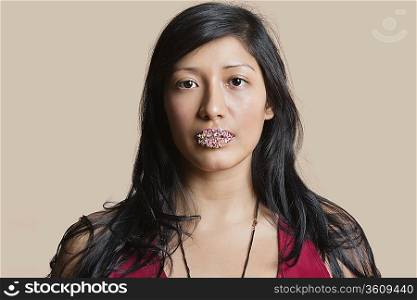 Portrait of a young woman with sweet sprinkles on lips over colored background