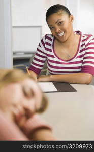 Portrait of a young woman writing in a notepad and smiling