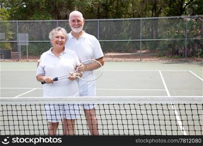 Portrait of active senior couple together on the tennis court.
