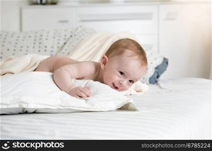 Portrait of adorable baby boy crawling on big bed at bedroom