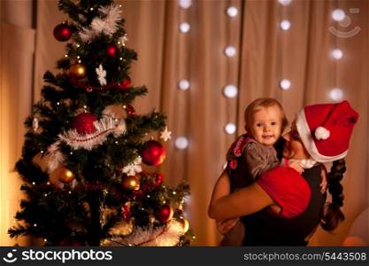 Portrait of adorable baby on mamas hand near Christmas tree&#xA;