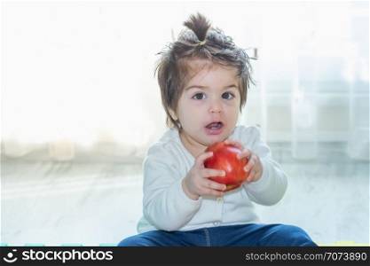 Portrait of adorable cute little baby girl toddler holding and eating a big red apple. Portrait of adorable cute little baby girl