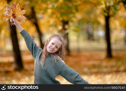 Portrait of adorable little girl in fall at autumn park outdoors. Portrait of adorable little girl with yellow leaves bouquet in fall