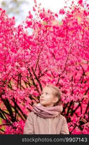 Portrait of adorable little girl outdoors at beautiful autumn day outdoors with amazing pink tree background. Adorable little girl at beautiful autumn day outdoors