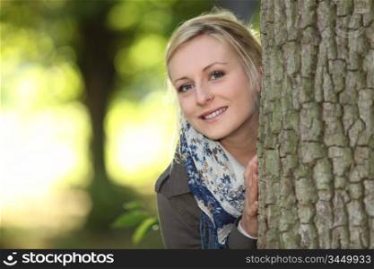 portrait of adorable young blonde outdoors with hands resting on bole