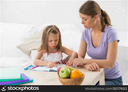 Portrait of adorable young girl and mother studying drawing at home