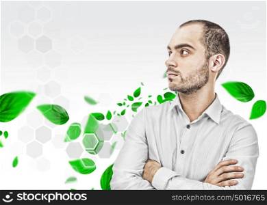 Portrait of adult business man standing with hands folded against digital background with green streaming leaves