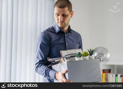 Portrait of adult caucasian man businessman wearing shirt holding a box personal items stuff leaving the office being fired from work due recession economic crisis downturn losing job company shutdown