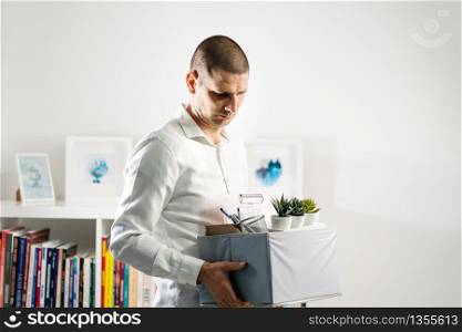 Portrait of adult caucasian man wearing white shirt holding a box personal items stuff leaving the office being fired from work due recession economic crisis downturn losing job company shutdown