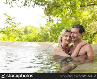 Portrait of adult couple embracing in pool smiling