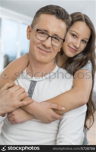 Portrait of affectionate girl embracing father from behind at home