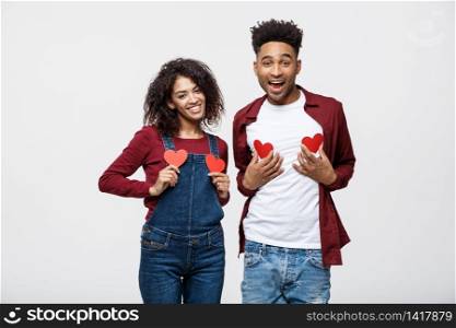 Portrait of african american cheerful couple holding red paper heart enjoy playing standing over grey background.. Portrait of african american cheerful couple holding red paper heart enjoy playing standing over grey background