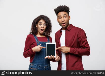 Portrait of African American couple holding table with shocking expression on white background.. Portrait of African American couple holding table with shocking expression on white background