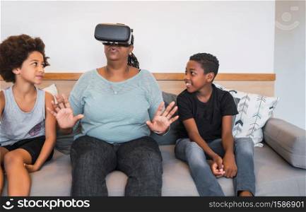 Portrait of African American grandmother and grandchildren playing together with VR glasses at home. Family and technology concept.
