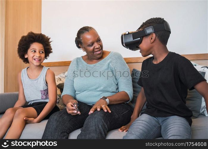 Portrait of African American grandmother and grandchildren playing together with VR glasses at home. Family and technology concept.