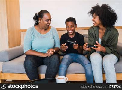 Portrait of African American grandmother, mother and son playing video games together at home. Technology and lifestyle concept.