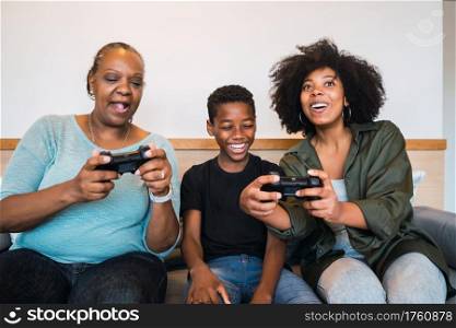 Portrait of African American grandmother, mother and son playing video games together at home. Technology and lifestyle concept.