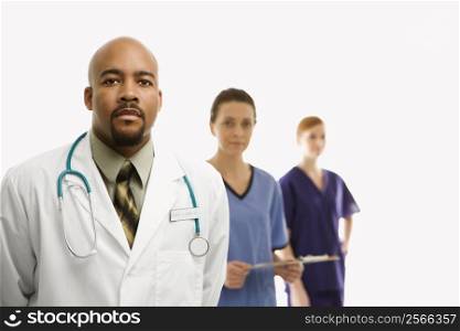 Portrait of African-American man and Caucasian women medical healthcare workers in uniforms standing against white background.