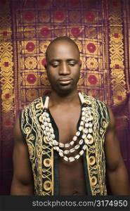 Portrait of African-American mid-adult man wearing embroidered African vest and beads.