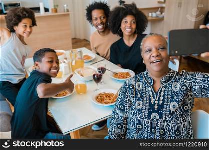 Portrait of african american multigenerational family taking a selfie together with mobile phone while having dinner at home. Family and lifestyle concept.