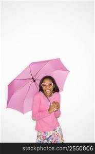 Portrait of African-American teen girl holding a pink umbrella standing in front of white background.