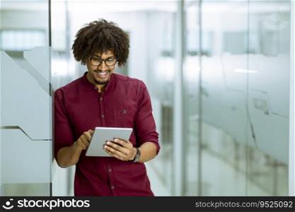 Portrait of african-american young businessman with tablet standing in the office