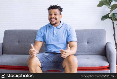 Portrait of African black man smiling and sitting on sofa in living room at home. Lifestyle Concept.