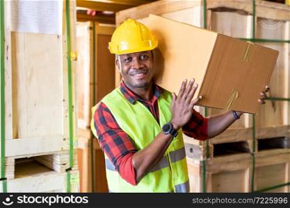 Portrait of african black warehouse worker hold cardboard box packaging on his shoulder in large warehouse distribution center environment. Using in business warehouse and logistic concept.