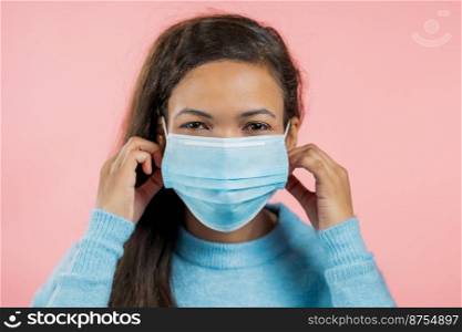 Portrait of african woman in protective mask. Lady on pink studio background. Coronavirus epidemic 2021. High quality photo. Portrait of african woman in protective mask. Lady on pink studio background. Coronavirus epidemic 2021
