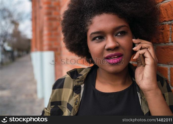 Portrait of Afro American latin woman talking on the phone outdoors in the street. Urban and communication concept.